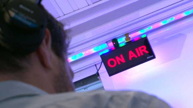 Un technicien radio devant un écran lumineux On Air
